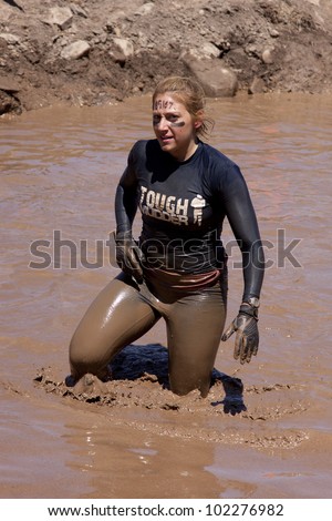 POCONO MANOR, PA - APR 29: A woman walks through a pit of mud and water at Tough Mudder on April 29, 2012 in Pocono Manor, Pennsylvania. The course is designed by British Royal troops.