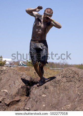 POCONO MANOR, PA - APR 29: A man loses his balance on the banks of a mud pit at Tough Mudder on April 29, 2012 in Pocono Manor, Pennsylvania. The course is designed by British Royal troops.