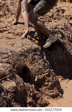 POCONO MANOR, PA - APR 29: A man climbs out of a pit of mud and water at Tough Mudder on April 29, 2012 in Pocono Manor, Pennsylvania. The course is designed by British Royal troops.