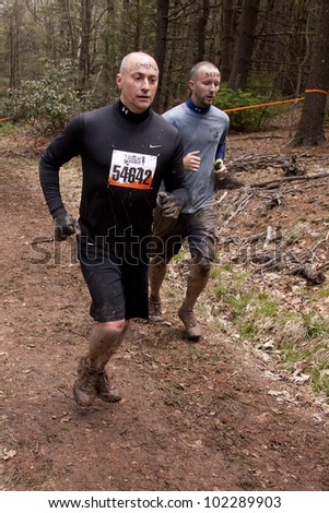 POCONO MANOR, PA - APR 28: Two men run on a trail through the woods at Tough Mudder on April 28, 2012 in Pocono Manor, Pennsylvania. The course is designed by British Royal troops.