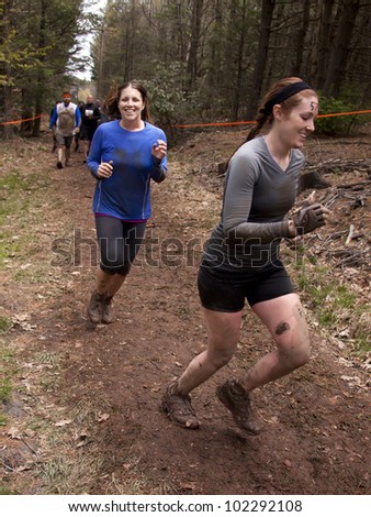 POCONO MANOR, PA - APR 28: Two women run on a trail through the woods at Tough Mudder on April 28, 2012 in Pocono Manor, Pennsylvania. The course is designed by British Royal troops.