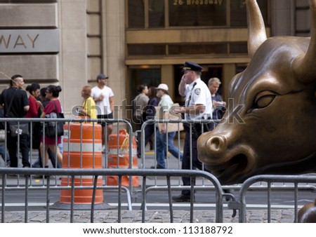 NEW YORK - SEPT 17: A policeman stands in front of the Charging Bull statue in lower Manhattan on the 1yr anniversary of the Occupy Wall St protests on September 17, 2012 in New York City, NY.