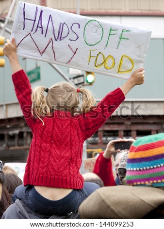 A young girl holds a sign that reads Hands Off My Food above the crowd during a march against genetically modified organisms, also known as GMO\'s.