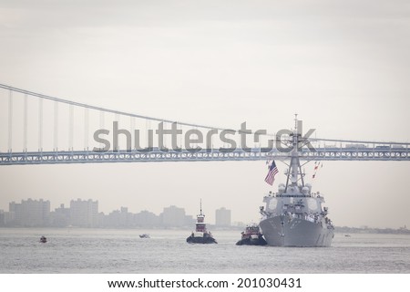STATEN ISLAND, NY - MAY 21, 2014: Guided-missile destroyer USS Cole (DDG 067) is guided into port at Sullivans Piers with the Verrazano-Narrows Bridge in the background. The ship is part of Fleet Week NY.