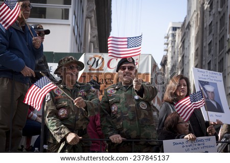 NEW YORK - NOV 11, 2014: US vets wave American Flags as they stand on a parade float in the 2014 America\'s Parade held on Veterans Day in New York City on November 11, 2014.