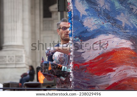 NEW YORK - NOV 11, 2014: American artist Scott LoBaido paints an American Flag on a large canvas in real time during the 2014 America\'s Parade on Veterans Day in New York City on November 11, 2014.