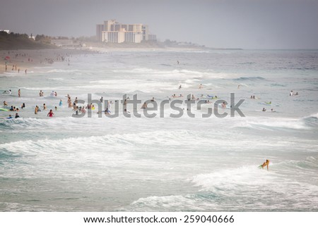JUNO BEACH, FL - APRIL 20, 2013: Swimmers and surfers enjoy the ocean waves and warm weather at Juno Beach, Florida.