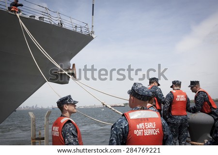 STATEN ISLAND, NY - MAY 20 2015: Sailors from NWS Earle Port Services tend the lines of the guided-missile destroyer USS Stout (DDG 55) as the ship docks at Sullivans Pier for Fleet Week NY.