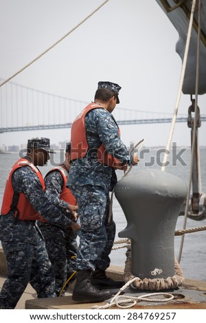 STATEN ISLAND, NY - MAY 20 2015: Sailors from NWS Earle Port Services tend the lines of the guided-missile destroyer USS Barry (DDG 52)  as the ship docks at Sullivans Pier for Fleet Week NY.