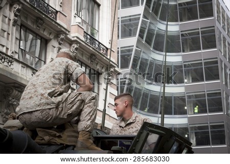 NEW YORK - MAY 21 2015: Two US Marines sit on top of a military tank parked on the street during a demonstration for the public at Bryant Park for Marine Day during Fleet Week NY.
