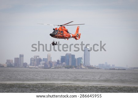 STATEN ISLAND, NY - MAY 24 2015: A Coast Guard rescue swimmer sitting in a rescue basket is hoisted into a USCG MH-65 Dolphin helicopter for a Search and Rescue demonstration during Fleet Week 2015.