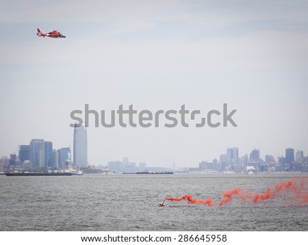 STATEN ISLAND, NY - MAY 24 2015: Orange smoke from a flare held by a rescue swimmer signals a US Coast Guard MH-65 Dolphin helicopter during a Search and Rescue demonstration for Fleet Week 2015.