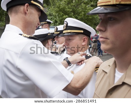NEW YORK - MAY 22 2015: A US Navy officer receives new shoulder boards during the promotion ceremony held at the National September 11 Memorial site during Fleet Week 2015.