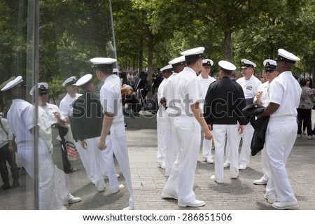 NEW YORK - MAY 22 2015: Reflection of US Navy officers in the glass of the the National September 11 Museum as they gather for the military re-enlistment and promotion ceremony during Fleet Week 2015.