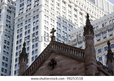The tops of spires of Trinity Church with modern buildings behind in New York City.