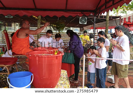 KUALA LUMPUR, MALAYSIA-MAY 13, 2014: Family are getting holy water blessing  from a priest at Buddhist Maha Vihara Temple during Vesak day at Kuala Lumpur Malaysia.