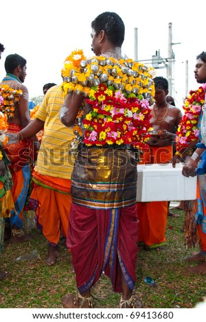 BATU CAVE, MALAYSIA - JAN 20 : An experienced man decorating a hindu devotee\'s body with dozens of tiny milk pots and flowers during Thaipusam on January 20, 2011 at Batu Cave temple, Malaysia.