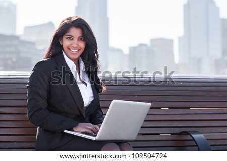 A shot of an Indian businesswoman working on her laptop outdoor