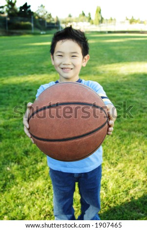 A happy boy handing a basketball (shallow DOF, focus on the ball)