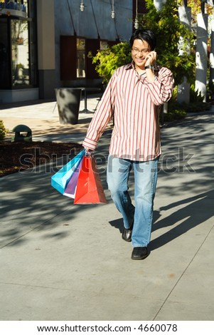 A young man talking on a cell phone while shopping at an outdoor mall