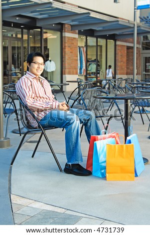 A young man with shopping bags in an outdoor shopping mall