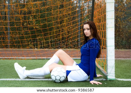 A beautiful soccer player posing with a soccer goal in front of the goal