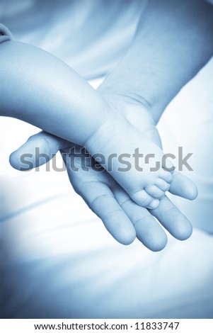 A shot of an adult hand holding a baby foot