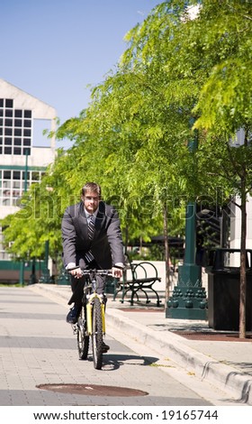 A caucasian businessman riding a bicycle to work, can be used for green or gas savings concept