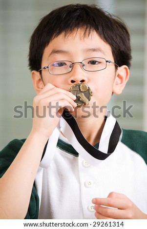 An asian boy kissing his winning sport medal