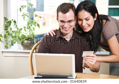 A happy couple holding a credit card shopping online