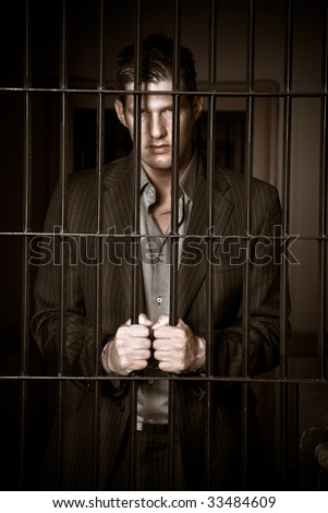 A caucasian businessman sitting in jail handcuffed