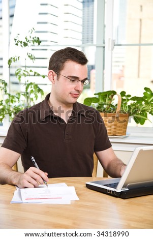 A caucasian man paying the bills by online banking at home