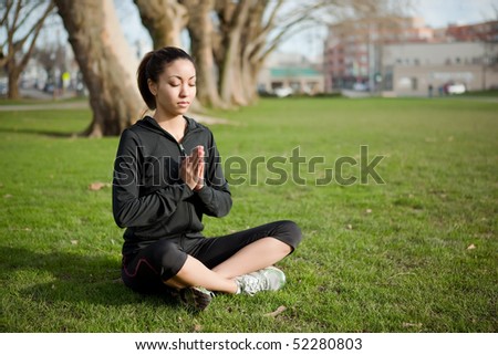 A beautiful black woman doing yoga meditation outdoor in a park