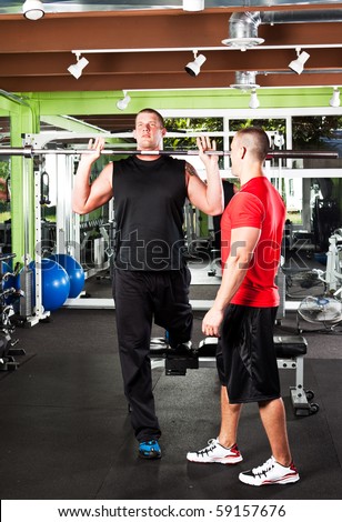A shot of a male personal trainer assisting a male athlete training