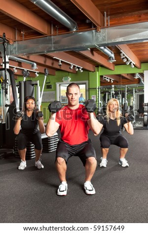 A shot of a male personal trainer training with two female athletes in the gym