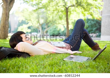 Mixed race college student sleeping on the grass at campus