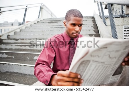 A portrait of a black businessman reading newspaper outdoor