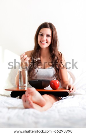 A shot of a beautiful girl eating breakfast in bed