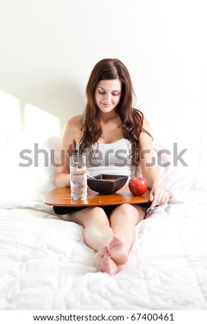 A shot of a beautiful girl eating breakfast in bed