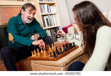 A shot of a senior caucasian male playing chess with his granddaughter