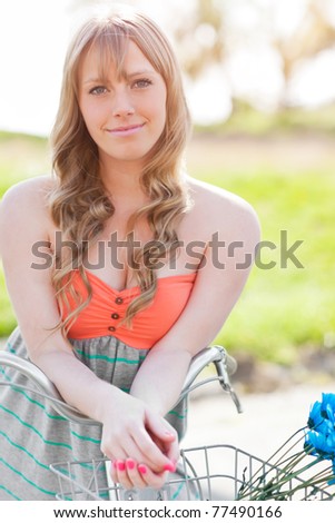 A portrait of a beautiful young Caucasian woman with her bike outdoor