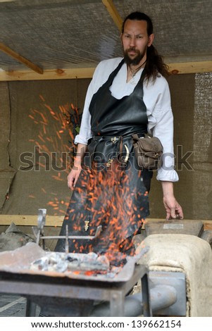 VILNIUS, LITHUANIA - MAY 24 : A blacksmith in medieval clothes, working in the street during a International Folklore Festival on May 24 2013 in Vilnius, Lithuania.