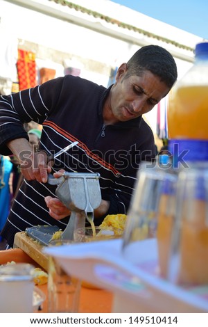 ESSAOUIRA - JULY 14: Unidentified man sells fresh orange juice in market of Essaouira, Morocco, July 14, 2013. Essaouira is one of the most popular tourist place on Atlantic coast in Morocco.