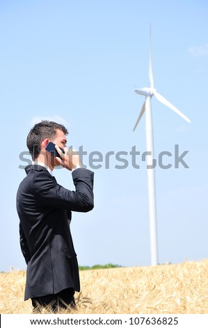 Business man with phone at wind mill