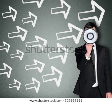 Young business man with loudspeaker and arrows pointing right