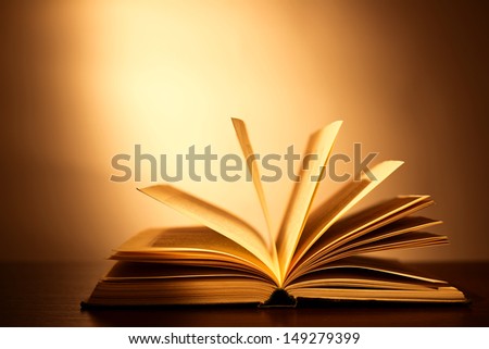 Hardcover book lying open on its cover with the pages fanned above it