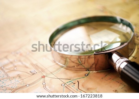 Handheld magnifying glass lying on a map conceptual of search, discovery , planning and exploration