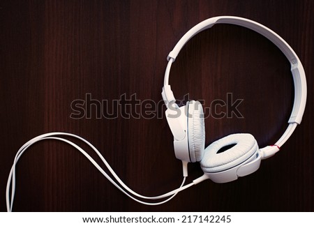 Set of modern white stereo headphones for listening to music on a storage device such as an MP3 player, on black