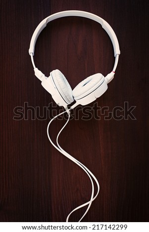 Set of modern white stereo headphones for listening to music on a storage device such as an MP3 player, on black