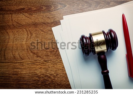 Wooden judges or auctioneers gavel and blank white paper lying on a wooden desk with a ballpoint pen in a concept of judgements or auction knock down, with copyspace